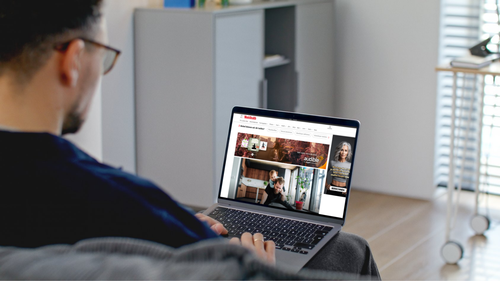 Mann liest auf einem Laptop einen nativen Artikel mit Audible-Anzeige auf der Website von Men’s Health.