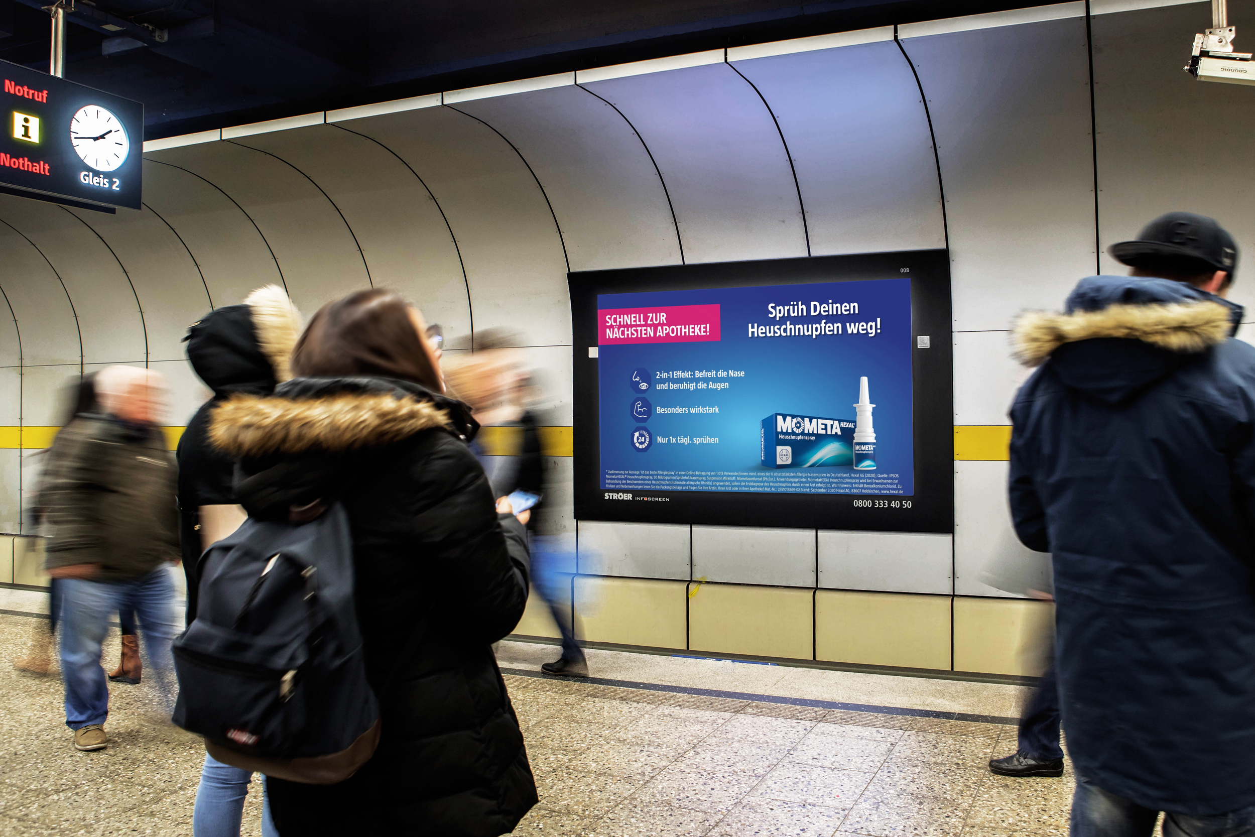 Digitale Werbetafel in U-Bahn-Station für MometaHEXAL® Allergiespray – Passanten warten auf die U-Bahn, während ein großer Bildschirm das Allergiespray MometaHEXAL® mit dem Slogan „Nr. 1 bei Allergiespray-Anwendern“ bewirbt.